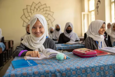 On 3 September 2023, a girl smiles with her textbook inside her primary class at Sorya High School in Kabul, Afghanistan.