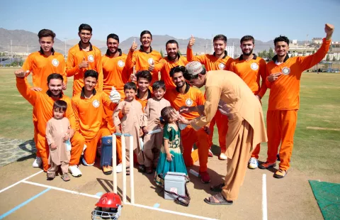 Children being vaccinated against Polio with the Maiwandi cricket players’ thumping support from behind during the inauguration of the nationwide Polio campaign at Kandahar cricket stadium in southern Afghanistan 