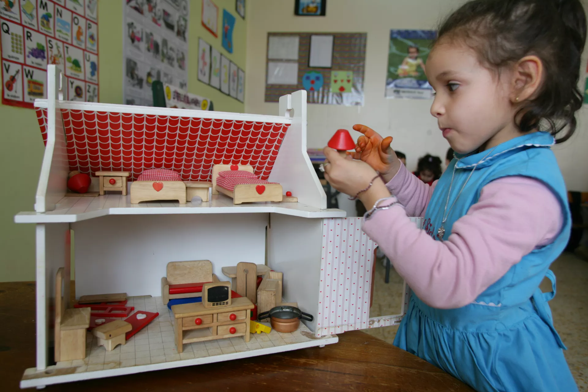 Petite fille joue avec une maison en bois