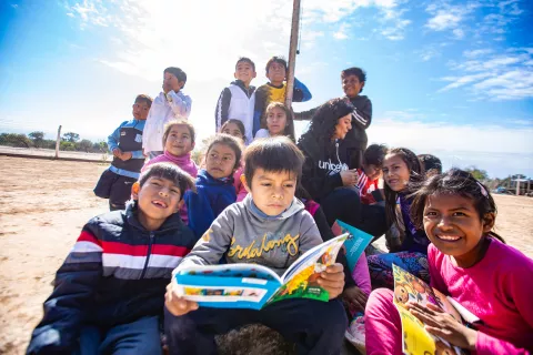 Un grupo de chicos y chicas leyendo en la entrada de su escuela