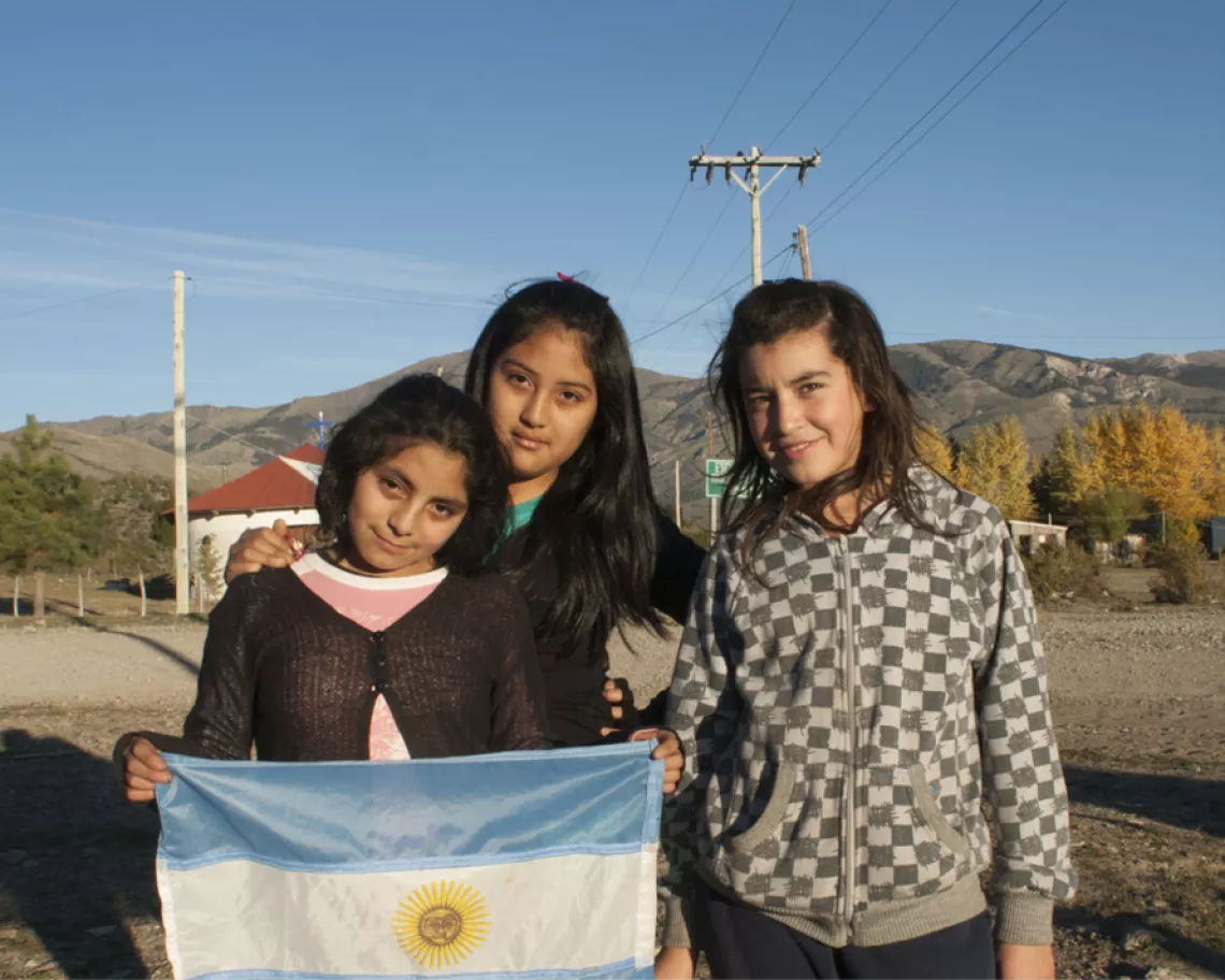 Niñas miran a cámara con una bandera argentina