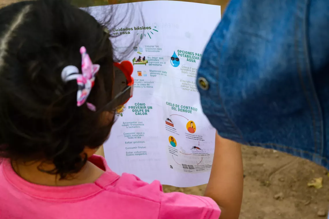 Una nena lee una recomendación para protegerse del dengue