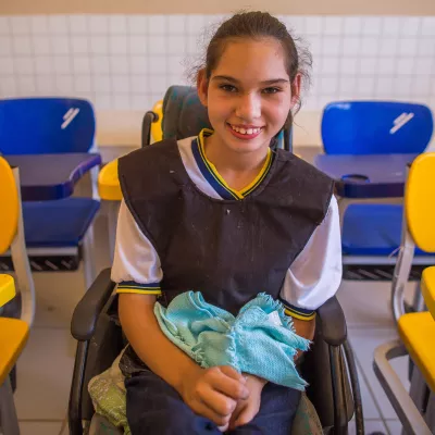 menina sentada em uma cadeira de rodas, na sala de aula