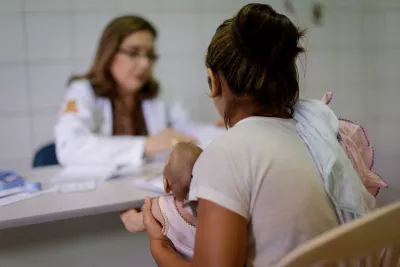 médica conversa com mãe que está com seu bebê no colo