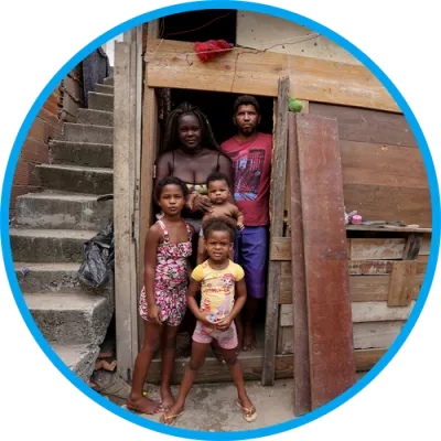 Foto mostra uma família parada em frente a uma porta