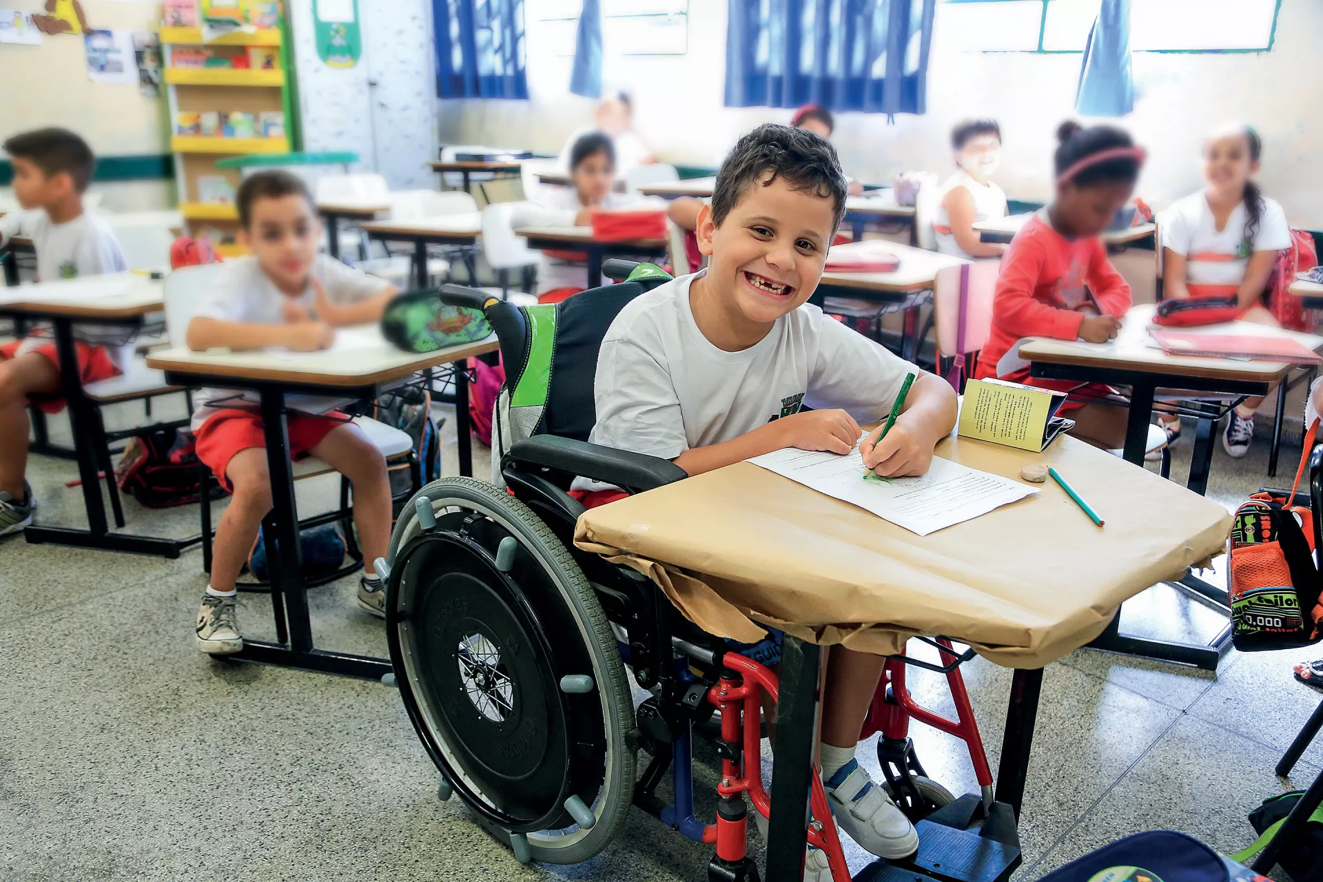 Menino que usa cadeira de rodas assiste à aula em escola regular