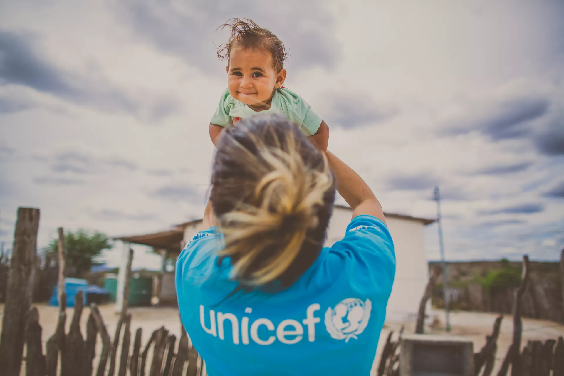 Funcionária do UNICEF ergue bebê no colo