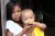 menina indígena ajuda bebê indígena a comer uma manga