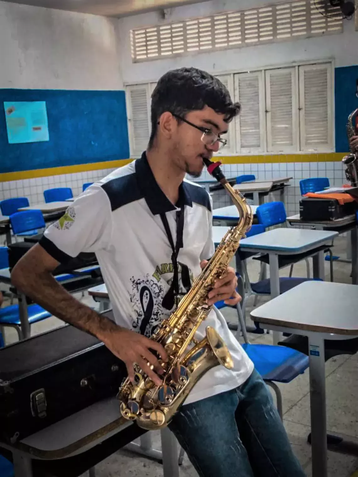 Foto mostra um adolescente tocando sax