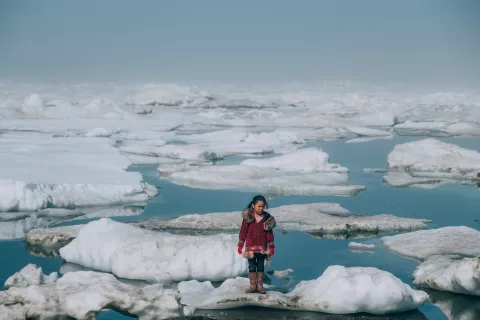 Момиче, стои върху пропукания лед в арктическия окен в Аляска, САЩ