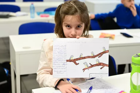 A Ukrainian girl shows her drawing in the classroom of the Ukrainian Education Hub in Sofia