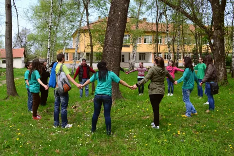 Деца, хванати за ръце, са заобиколили в кръг едно дърво