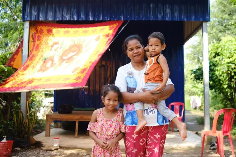A lady with two children in front of her house