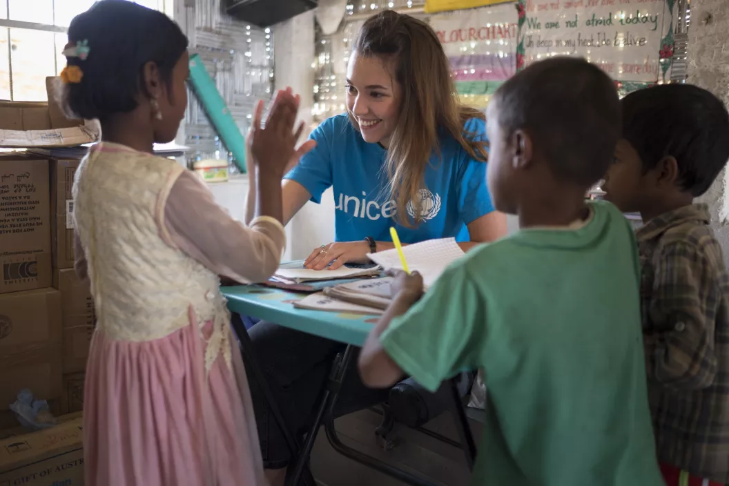 A female UNICEF staff high five with children