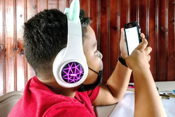 Kid with headphones using a cellphone