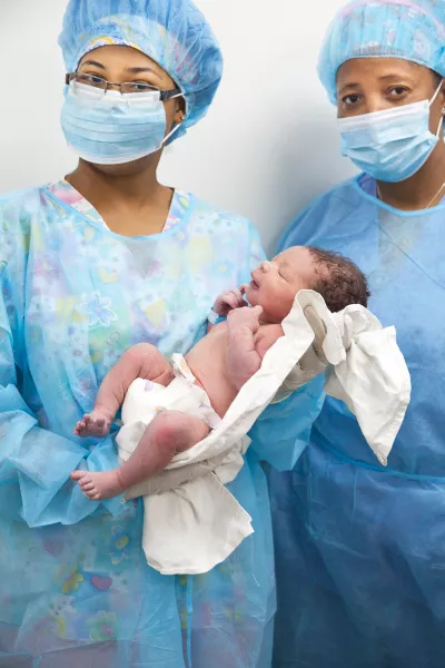 Médicos sosteniendo a un bebé recién nacido.