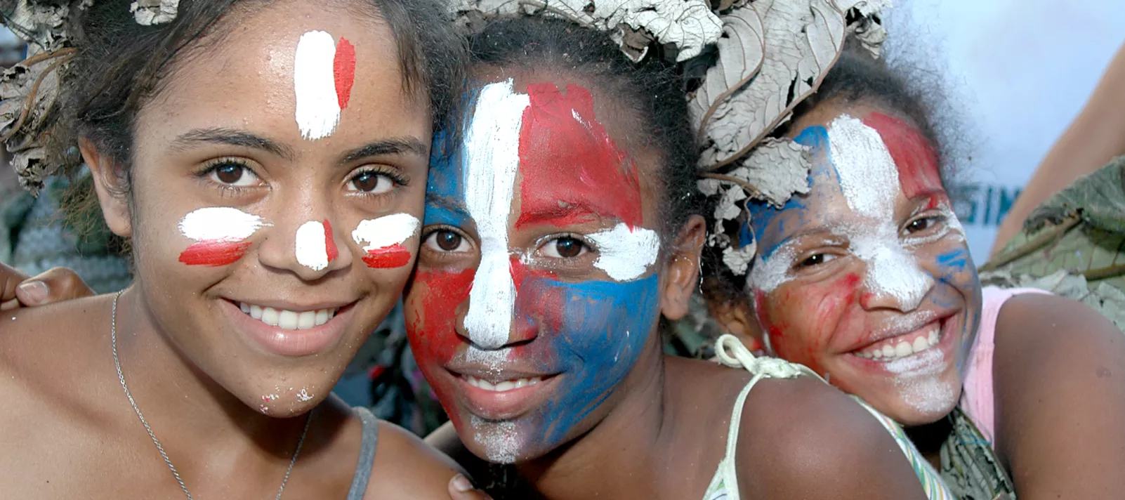 Niñas con la cara pintada con los colores de la bandera de República Dominicana.