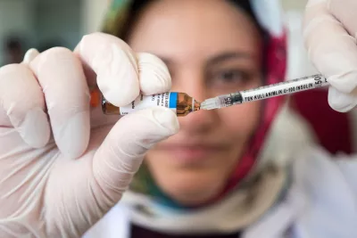 A woman loads vaccine into a syringe