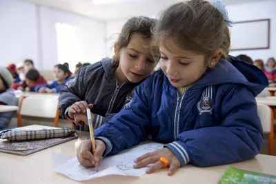 Children at a refugee centre in Turkey draw on paper at a school