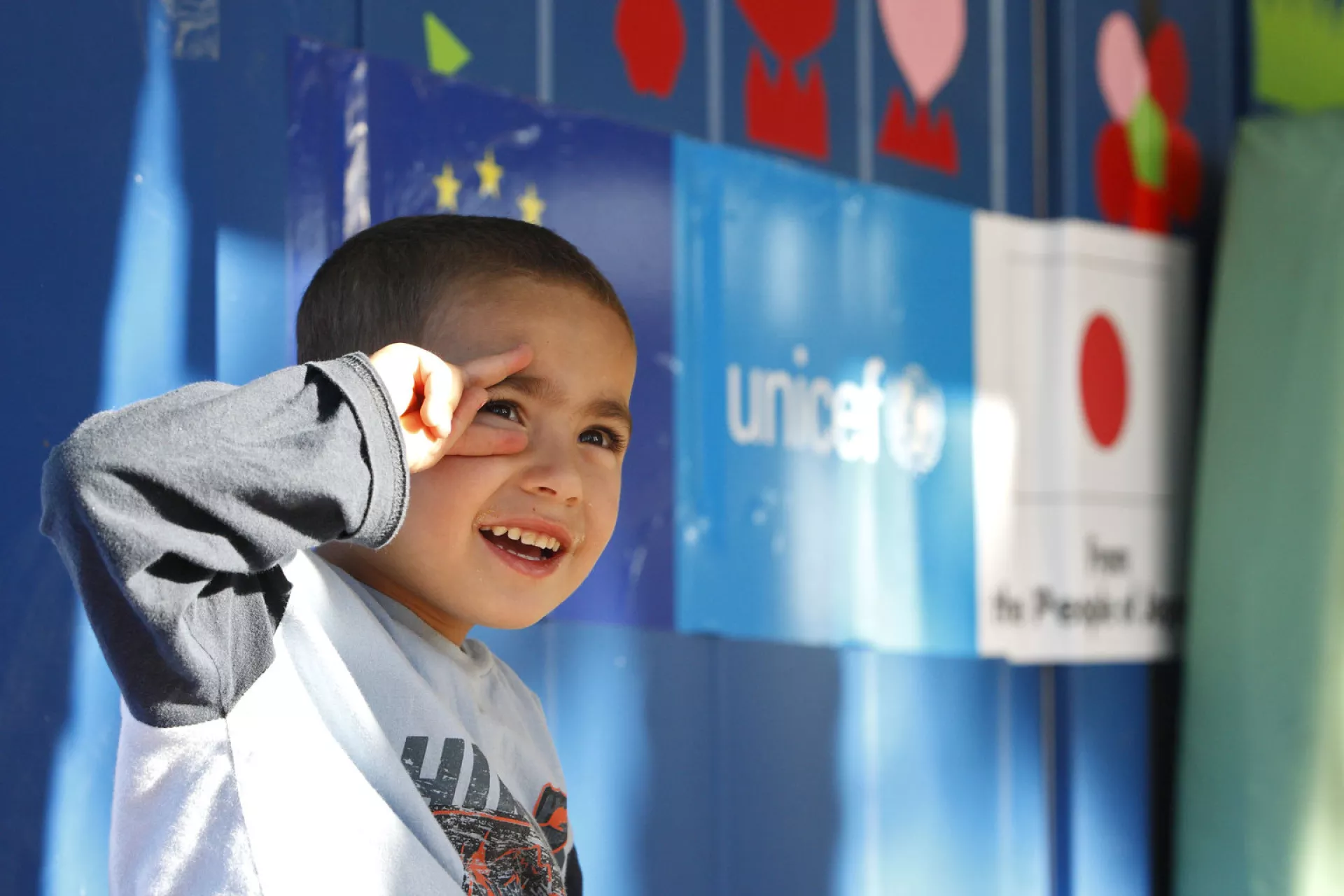 Four-year-old Mahmud from Syria sits enjoying a lovely sunny day in front of a UNICEF child-friendly space in Serbia 