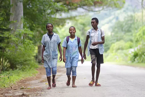 Three adolescents walking together on a rural road