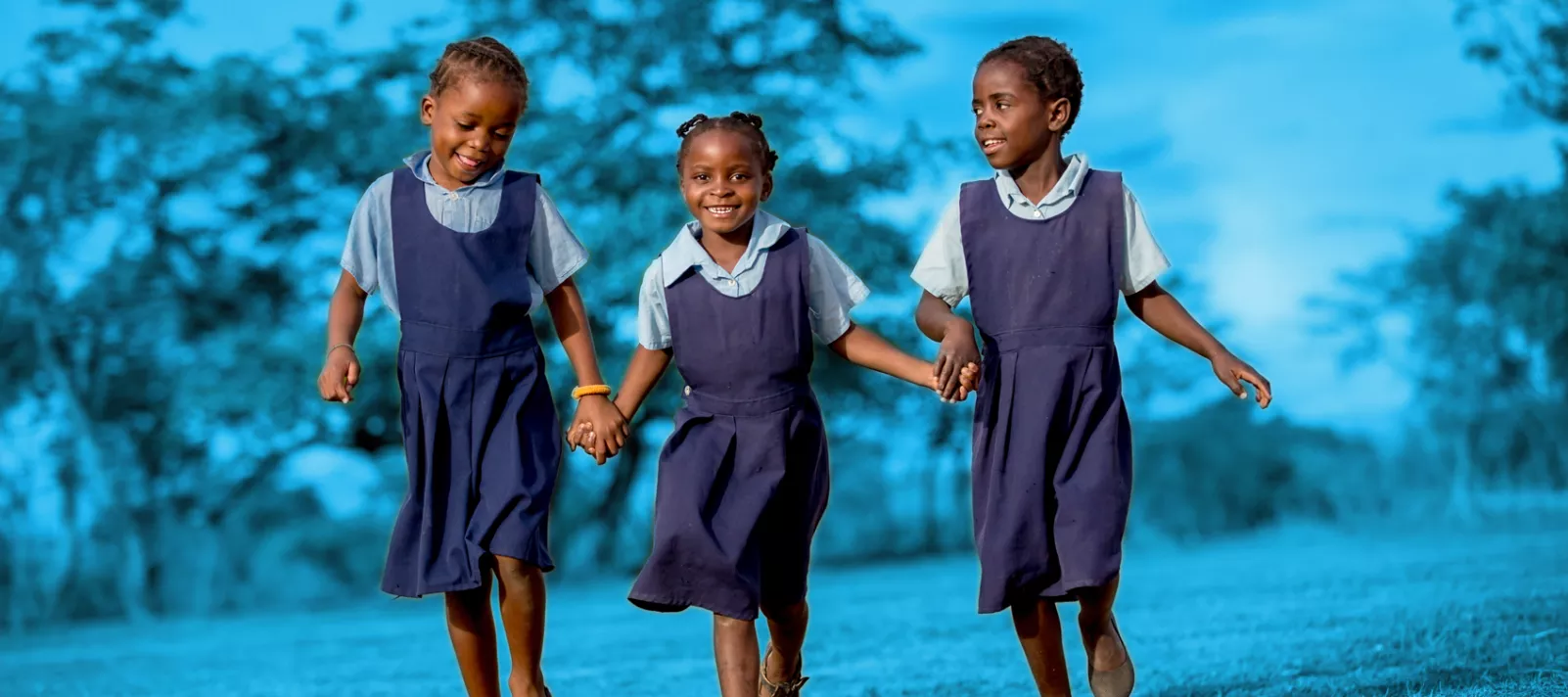 Young girls hold hands while playing outdoors at Chimowa Primary School in Monze, Zambia.