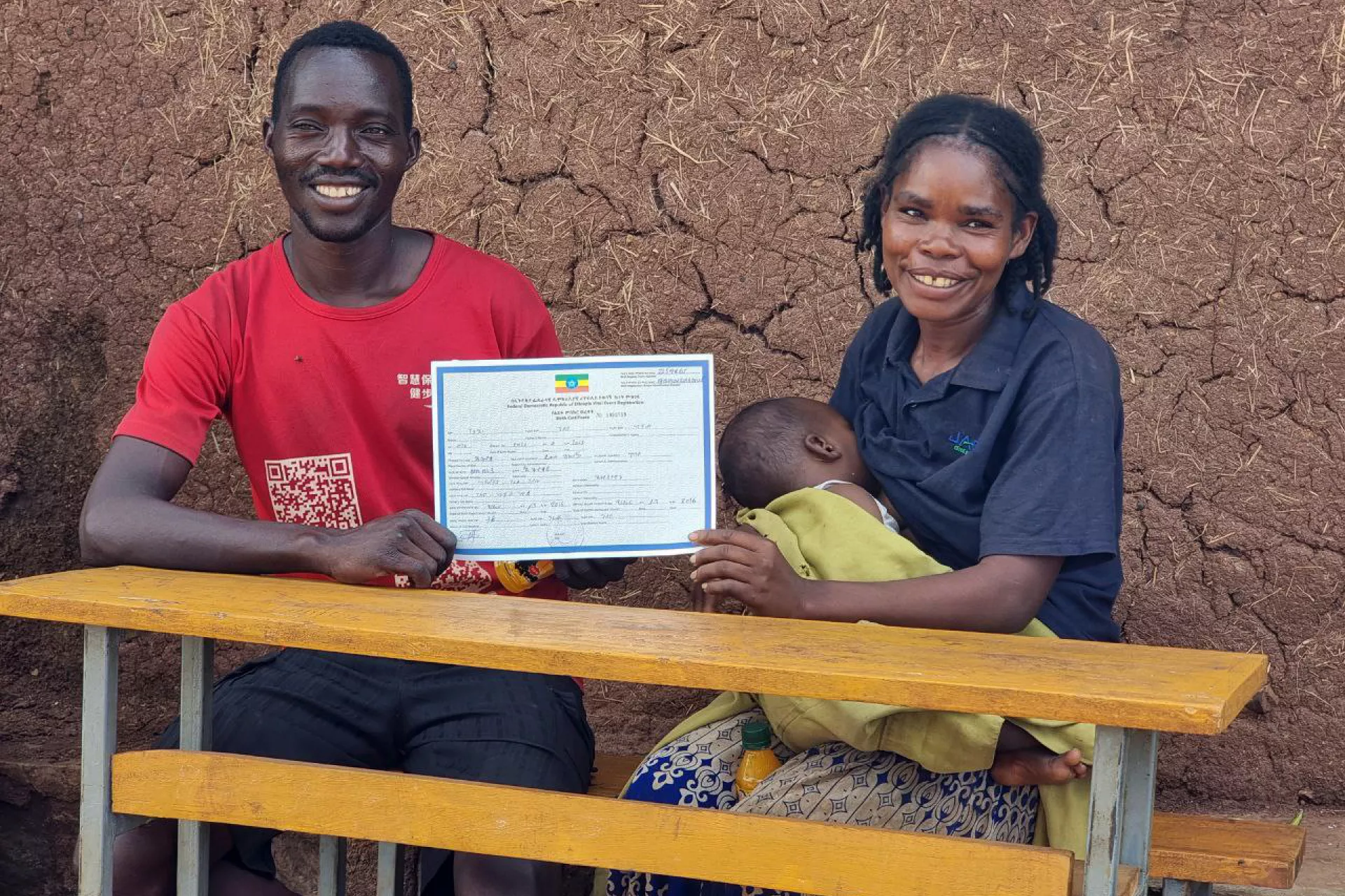 A man and women holding her baby and sitting together and holding a birth certification