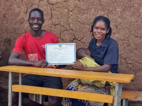 A man and women holding her baby and sitting together and holding a birth certification