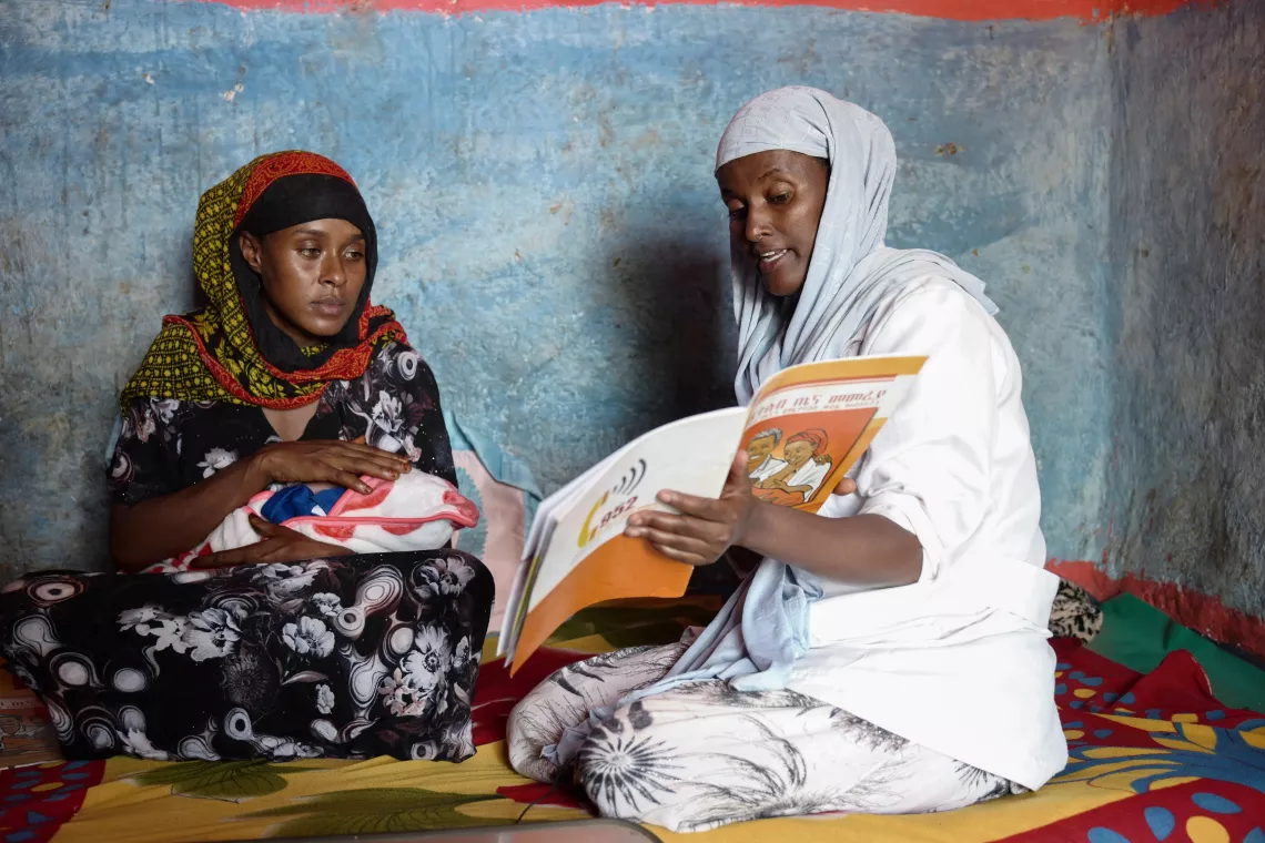 A health worker teaching a new mother with a family planning document