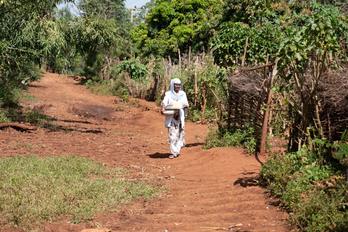 A health worker walking in a village with her health equipment's