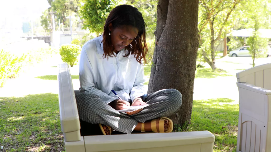 A young girl siting on a bench and processing her experiences in poems. 