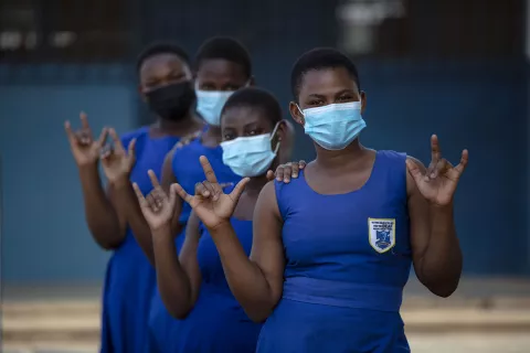 Adolescent girls in blue school uniform wearing face masks.