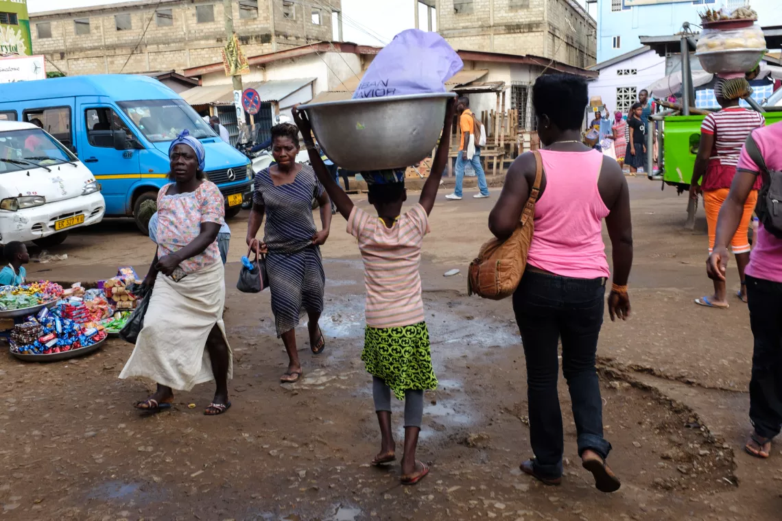 A young kayayo (femal head porter) carrying a customer's load through Madina Market in Accra, Ghana on 6 May 2015.  