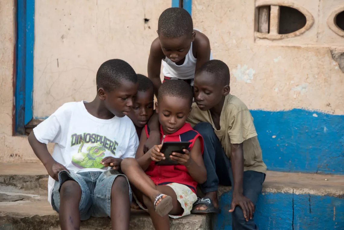 Children huddle around a tablet playing video games