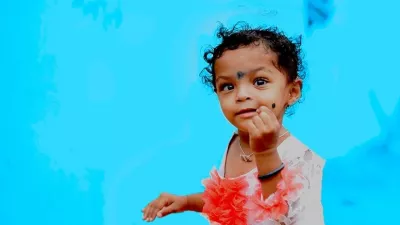 A girl child plays with a blue background behind her