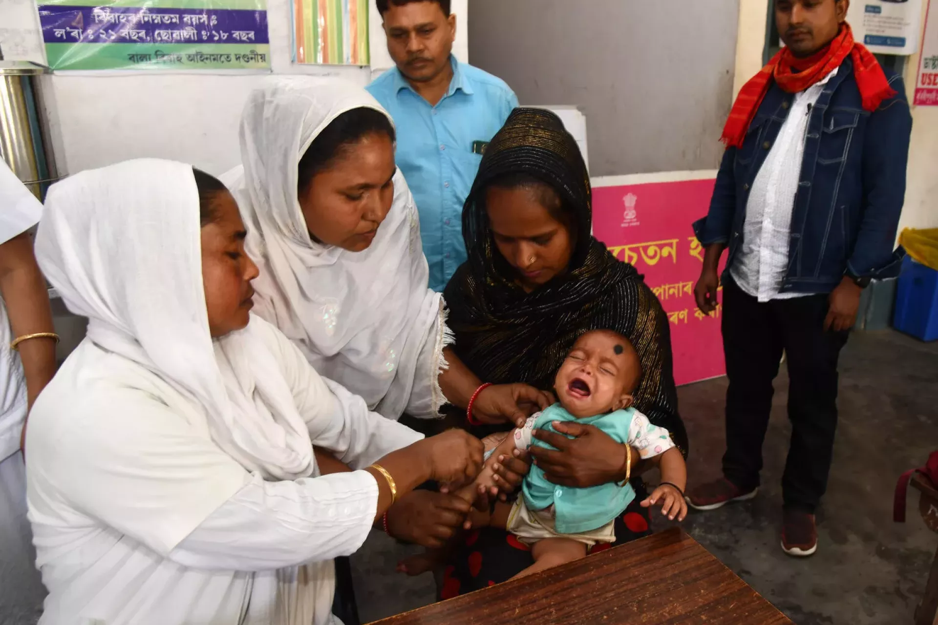 Auxiliary Nursing Midwife (ANM) and health workers give a vaccine to Arifa Janat, one-month-old, during the routine immunisation (RI) sessions 