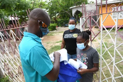 Photograph: Principal of Little Bay Primary and Infant School in Westmoreland, Keron King, hands over lessons to Kaedia Ellis Johnson with her daughter and student Sasheena Johson on Monday, September 7, 2020.