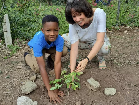 Photograph of UNICEF Jamaica Representative Olga Isaza and Climate Action Advocate Jaeden, 10, participating in a tree planting at Hope Valley Experimental School in St Andrew on Wednesday, April 19 2023.