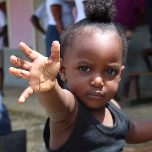 Photograph of a toddler reaching out her hand