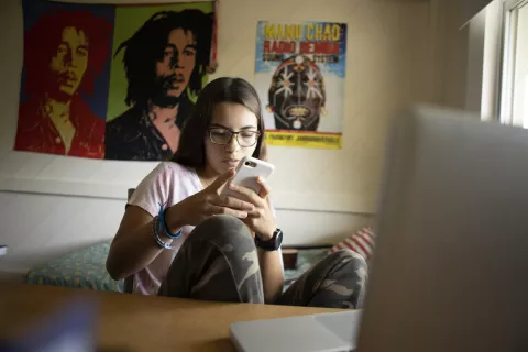 Una adolescente se comunica con sus amigos por celular.