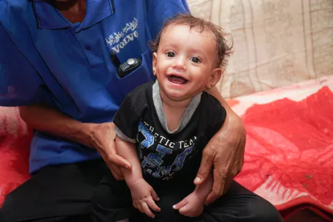 Yahya, a UNICEF Yemen volunteer, holds his child in the Al Sha'ab Camp in Aden, Yemen on 16 October 2021.