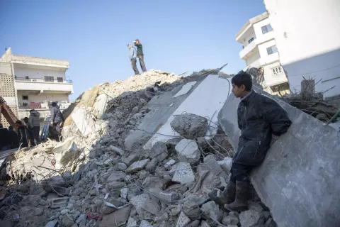 Syria. A boy stands by the remains of collapsed buildings in Jableh district, northwestern Syria.