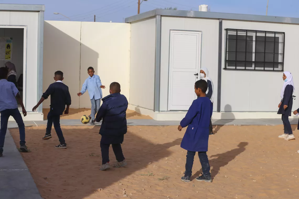 Playtime at Taqrouteen School on newly renovated grounds, where students enjoy a game of football on the freshly added sidewalks.