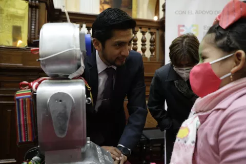 Un maestro muestra un robot a una niña