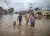 Una familia camina por una calle inundada por lluvias