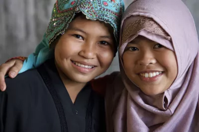 Two girls wearing hijabs smile in front of the camera