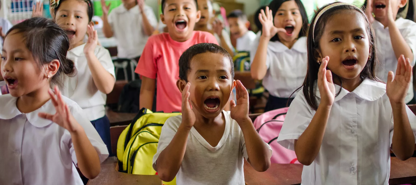 Children stand up and and yell during a class activity inside a classroom