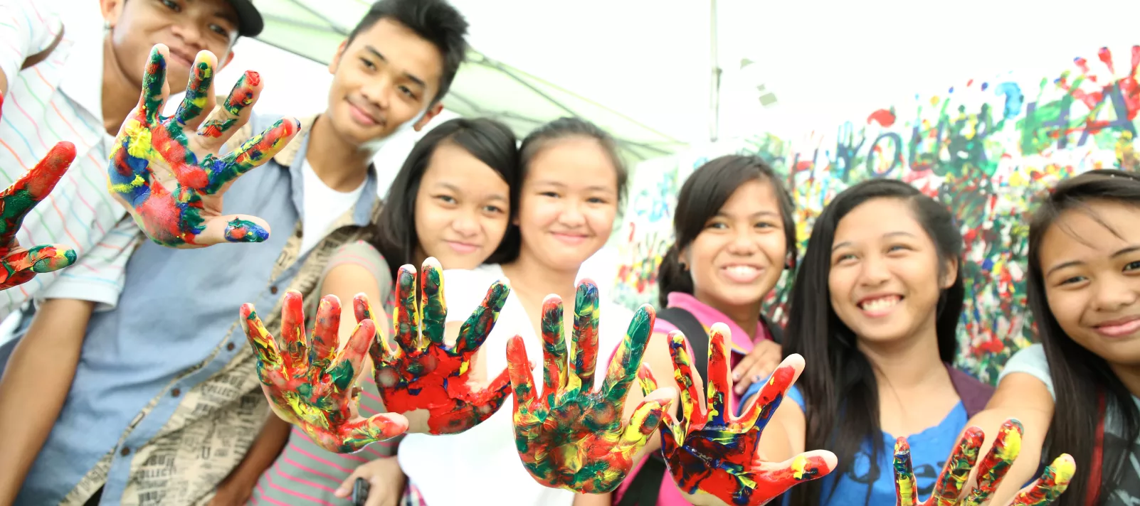 Adolescents show their palms with paint at a mural painting session