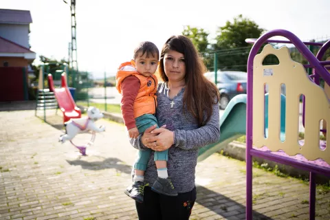 A mother holds her child in front of a playground