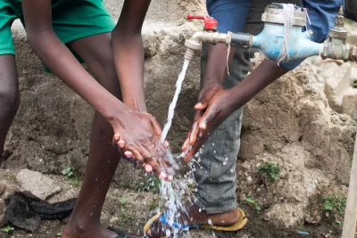 Two young boys in Rwanda wash their hands with clean water